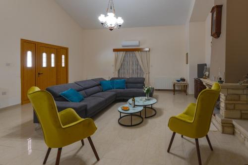 a living room with a blue couch and yellow chairs at Eidyllio ''The Mansion'' in Omodos