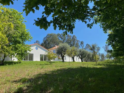 a house in a field with trees in the foreground at Catrinandes - Retreat Center in Tondela