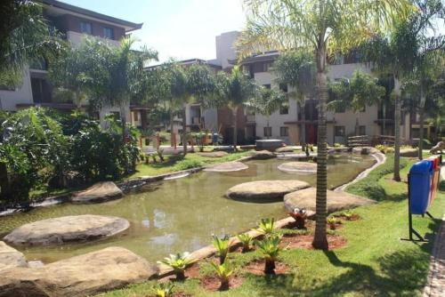 巴西利亞的住宿－L209 Apto em resort beira lago com TV Smart，一座花园,在一座建筑前设有一个池塘
