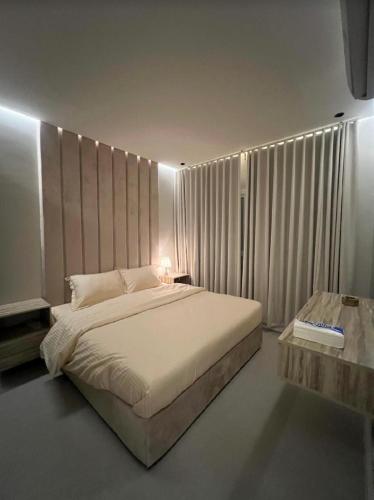 um quarto com uma grande cama branca e uma mesa em شقق سمارت انترى بالملقا em Riyadh