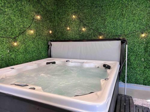 eine Badewanne mit grüner Wand und Licht in der Unterkunft Upscale Urban Oasis: Spacious & Chic with Hot Tub! in Traverse City