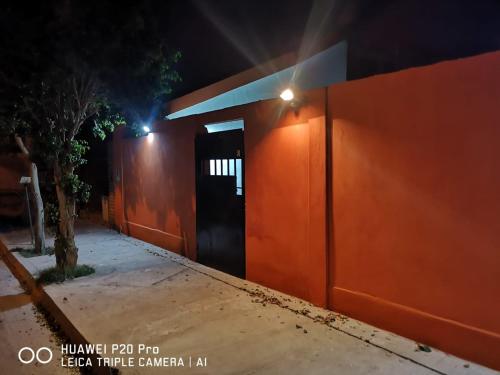 un edificio naranja con una puerta negra por la noche en Bruna Departamentos en San Fernando del Valle de Catamarca