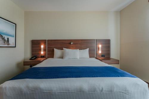 a bedroom with a large bed with a blue blanket at La Venta Inn Ciudad del Carmen in Ciudad del Carmen