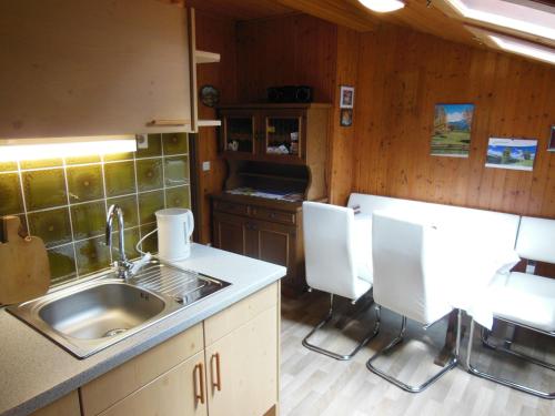 a kitchen with a sink and white chairs in it at Ferienwohnung Dirlinger by Schladmingurlaub in Schladming