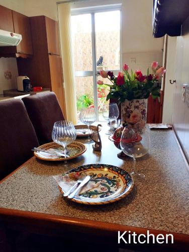 a table with plates and glasses and a vase of flowers at "Spirit of Malta" Historic Maltese Townhouse by the sea in Sliema