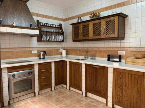 eine Küche mit Holzschränken und einem Waschbecken in der Unterkunft Casa Emigrantes in Montejaque