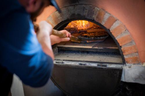 una persona está poniendo una pizza en un horno en Hacienda Real San Miguel de Allende, en San Miguel de Allende