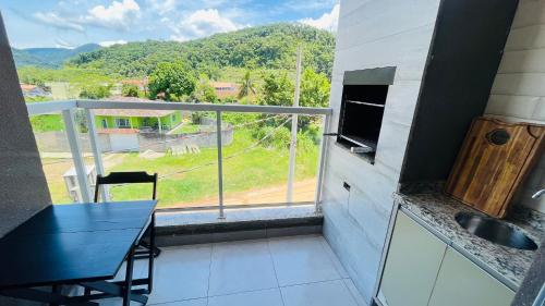 eine Küche mit einem Tisch und einen Balkon mit Aussicht in der Unterkunft Apto novo com piscina em Ubatuba - Praia Maranduba in Ubatuba