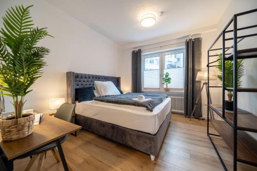 1 dormitorio con cama, mesa y planta en City Wohlfühloase - FeWo Berger, en Bielefeld