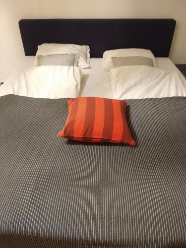 Una cama con una almohada naranja encima. en COZY STUDIO CENTRAL, en Helsingborg