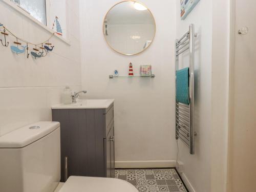 Un baño con inodoro, lavabo y espejo. en 3 Dolphin Court, en Brixham