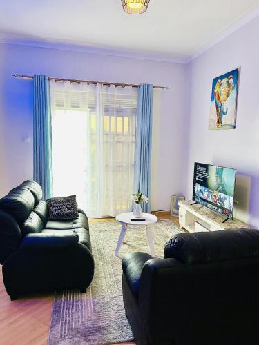 sala de estar con 2 sofás y TV en Cyda Orchid Home-Buziga-Munyonyo, en Kampala