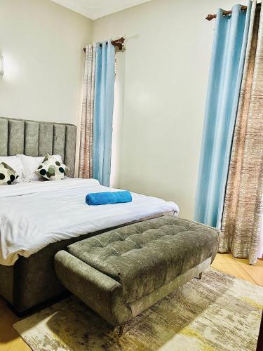 1 dormitorio con cama con cortinas azules y sofá en Cyda Orchid Home-Buziga-Munyonyo, en Kampala