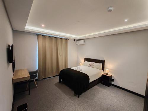 ein Schlafzimmer mit einem Bett, einem Tisch und einem Stuhl in der Unterkunft Durban Boutique Hotel in Durban