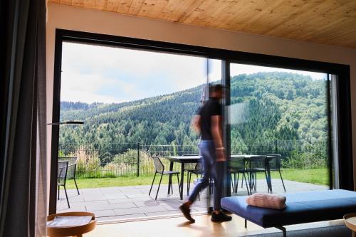 a man walking in front of a large glass door at Sauerland Lodge - Haus Maxim in Winterberg