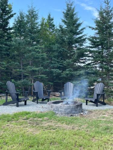 three park benches sitting around a fire pit at Modern waterfront cottage +hot tub in Marion Bridge
