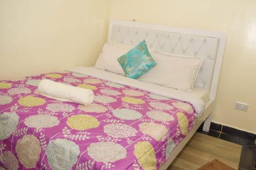Cama con manta y almohadas de color púrpura y blanco en Fully furnished One bedroom bnb in Thika Town. en Thika