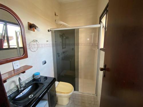 a bathroom with a shower and a toilet and a sink at Casa do Bert in Itanhaém