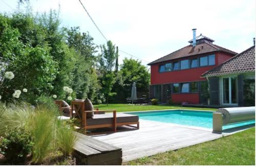 einen Hinterhof mit einem Pool und einem Haus in der Unterkunft Maison d'architecte idéalement située pour les JO in Neauphle-le-Château