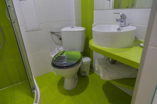 a green and white bathroom with a toilet and a sink at Hotel GabriSa in Razgrad