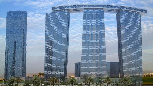 two tall buildings in a city with palm trees at Dinar Home in Abu Dhabi