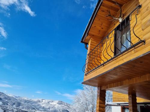a balcony on the side of a log house with snow covered mountains at La casa din deal in Vişeu de Sus