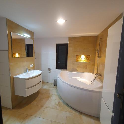 a large white bathroom with a tub and a sink at La casa din deal in Vişeu de Sus