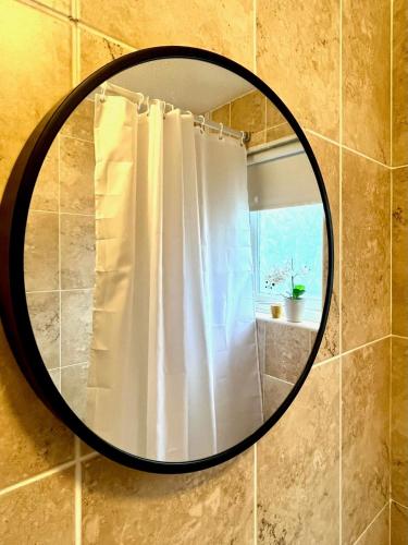 a mirror in a bathroom with a shower curtain at 1 Bed - Sleeps 4 - Parking - 15 mins Gatwick in Crawley