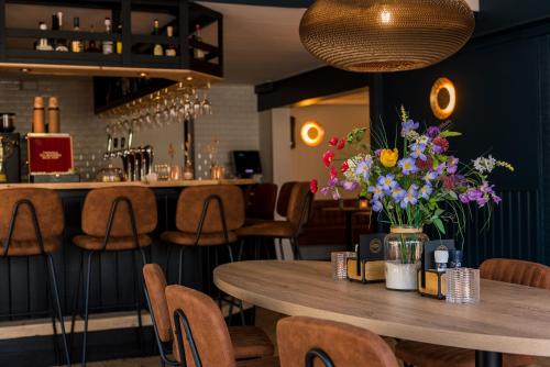 un restaurante con una mesa de madera con flores. en Hotel-Brasserie De Walvisvaarder en Hollum