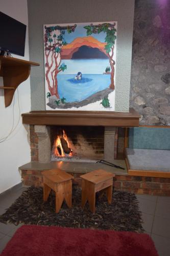 a fireplace with a fire place with a painting at Potamolithos Suites in Konitsa