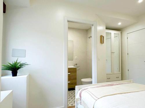 a white bedroom with a bed and a bathroom at Apartamento de diseño en Laredo centro in Laredo