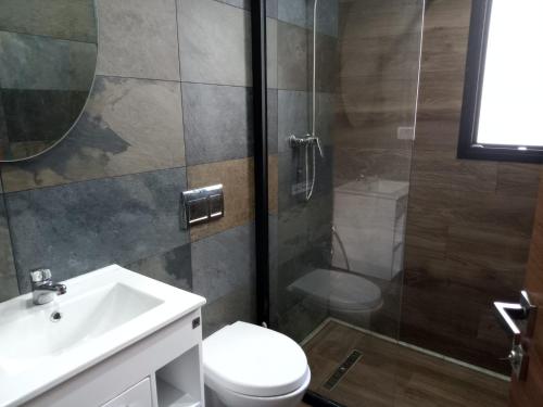 een badkamer met een douche, een toilet en een wastafel bij Esmeralda in Douar el Hafey