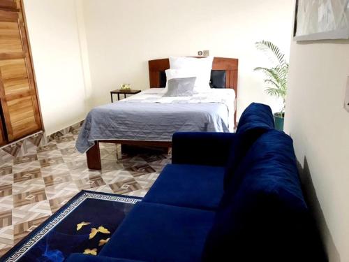 sala de estar con sofá azul y cama en Apartment PARIS, en Yaoundé