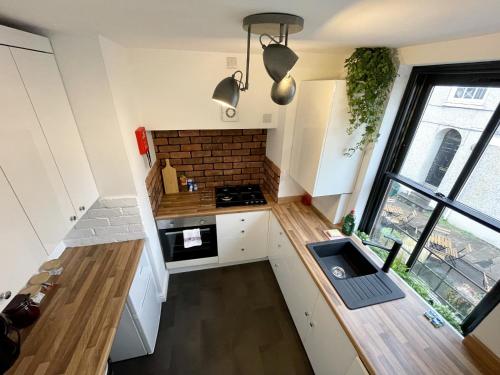 uma pequena cozinha com armários brancos e uma parede de tijolos em Cosy Oasis in the Heart of Clifton Village em Bristol