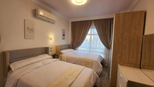 um quarto de hotel com duas camas e uma janela em Madinaty apartment شقة فندقية مفروشة سوبر لوكس في مدينتي em Madinaty
