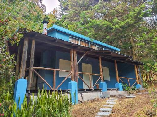 ein blaues Haus mit Bäumen im Hintergrund in der Unterkunft Oasis del Bosque 