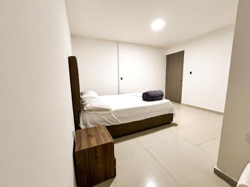 Habitación pequeña con cama y banco de madera. en Hotel y Restaurante Oasis CTG en Cartagena de Indias