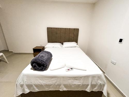 Un dormitorio con una gran cama blanca con una bolsa negra. en Hotel y Restaurante Oasis CTG, en Cartagena de Indias