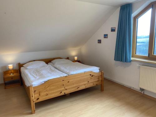 1 dormitorio con 1 cama con sábanas blancas y ventana en Ferienhäuser am Vogelpark - Boddenhaus Tizi, en Marlow