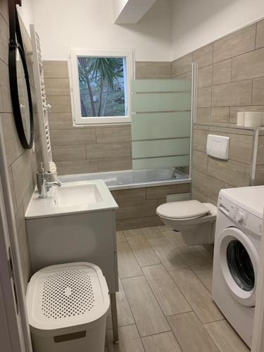 une salle de bain avec un lavabo et une machine à laver dans l'établissement L'alivu di porto vecchio*** ( piscine chauffée ), à Porto-Vecchio