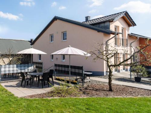 eine Terrasse mit Tischen und Sonnenschirmen vor einem Haus in der Unterkunft Holiday home with terrace near volcanic lakes in Ellscheid