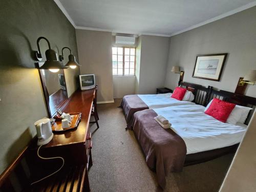 Habitación de hotel con cama grande y escritorio. en Pietersburg Club en Polokwane