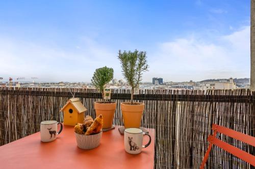 une table avec des tasses et une maison d'oiseaux sur un balcon dans l'établissement Appartement Scandicci vue fantastique - Welkeys, à Pantin