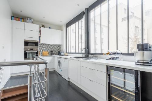 uma cozinha com armários brancos e uma grande janela em Loft spacieux à 10 minutes Champs-Élysées em Levallois-Perret