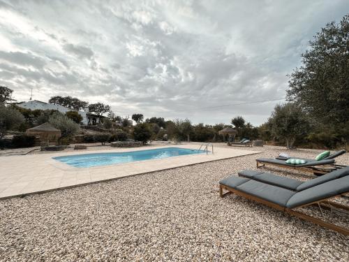 a swimming pool with two lounge chairs next to it at Corvatos Casas do Monte in Almodôvar
