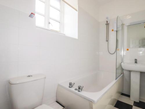 a white bathroom with a tub and a sink at Roughtor Cottage in Bodmin