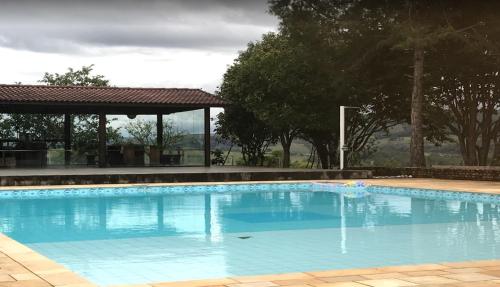 a large blue swimming pool with a gazebo at Fazenda e Vinícola ABN in Andrelândia