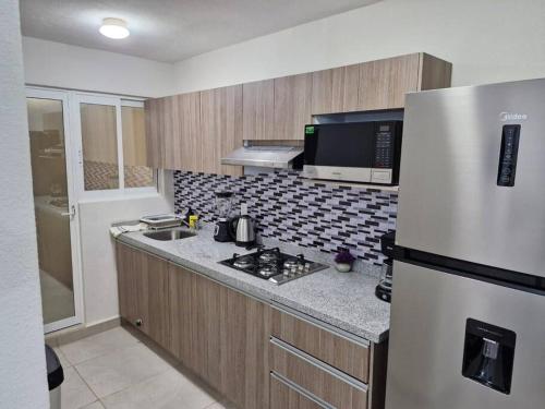 a kitchen with a stainless steel refrigerator and a sink at Depto. con club de Playa in Acapulco
