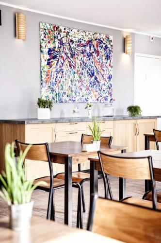 a restaurant with tables and chairs and a large painting on the wall at Hôtel Des Argousiers in Ambleteuse