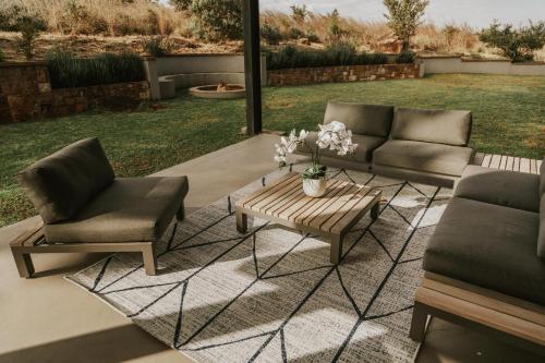 a patio with two chairs and a coffee table at Sensiri Myst Country House in Dullstroom
